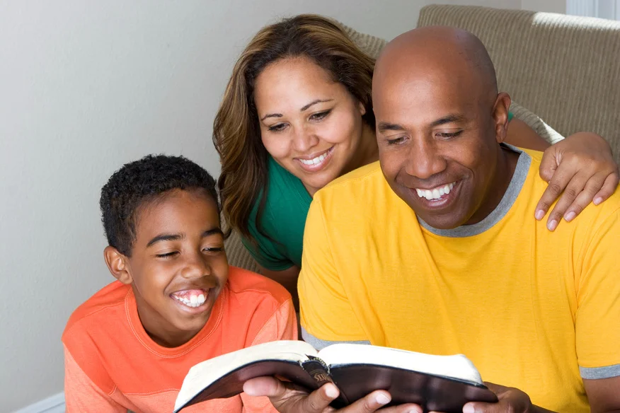 man, woman, and teenage boy reading book on stairs